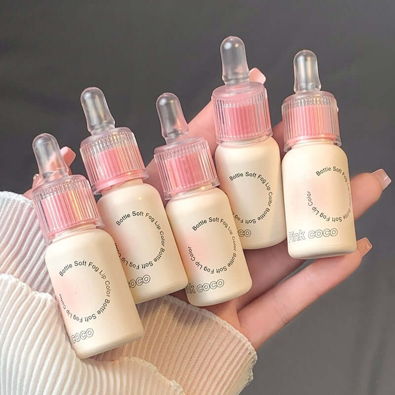 Five bottles of lip gloss in pastel packaging held in hand, featuring moisturizing and colored options.