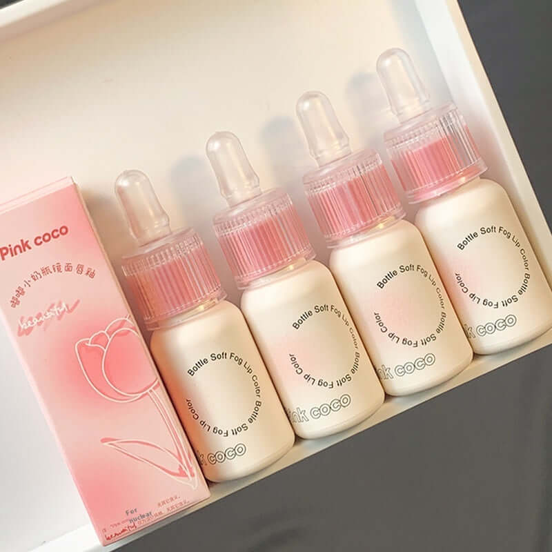 Four bottles of Pink Coco soft lip gloss on display with elegant packaging in soft pink tones.