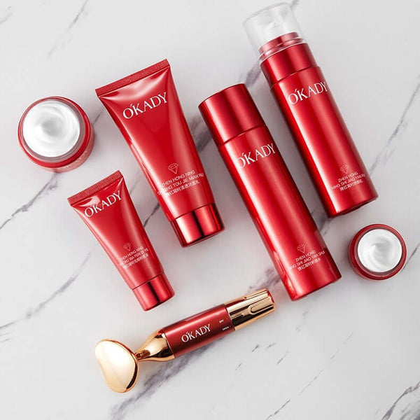 High-end skin care products in red packaging, including cleansers, creams, and serums, arranged on a marble surface.