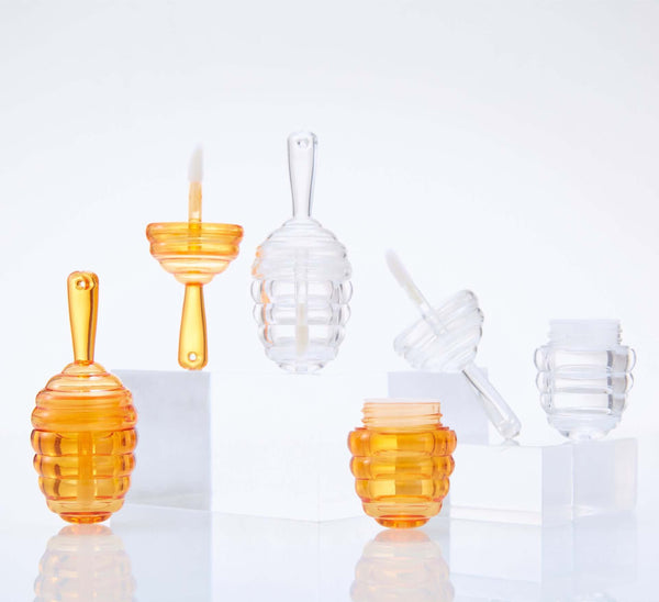 Mini Bee Fang honeycomb lip gloss tubes in orange and clear plastic, featuring leak-proof design and stylish elegance.