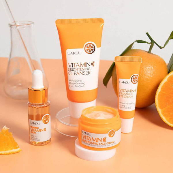 Vitamin C Skin Care Set with cleanser, eye cream, and face cream alongside fresh oranges on a peach background.